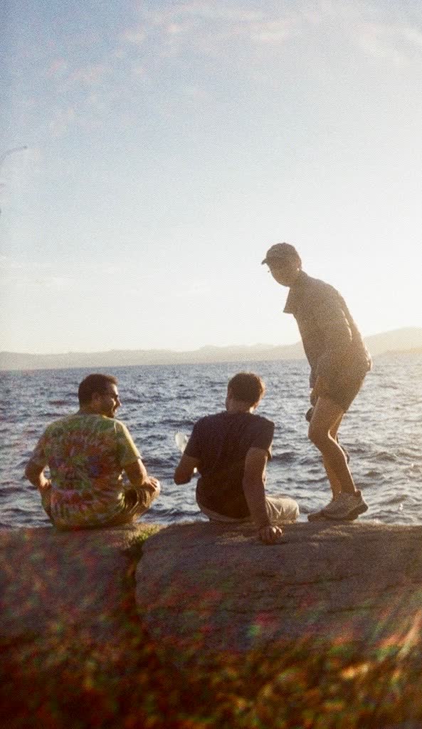 The Attractor Labs team sitting on rocks by the water at golden hour